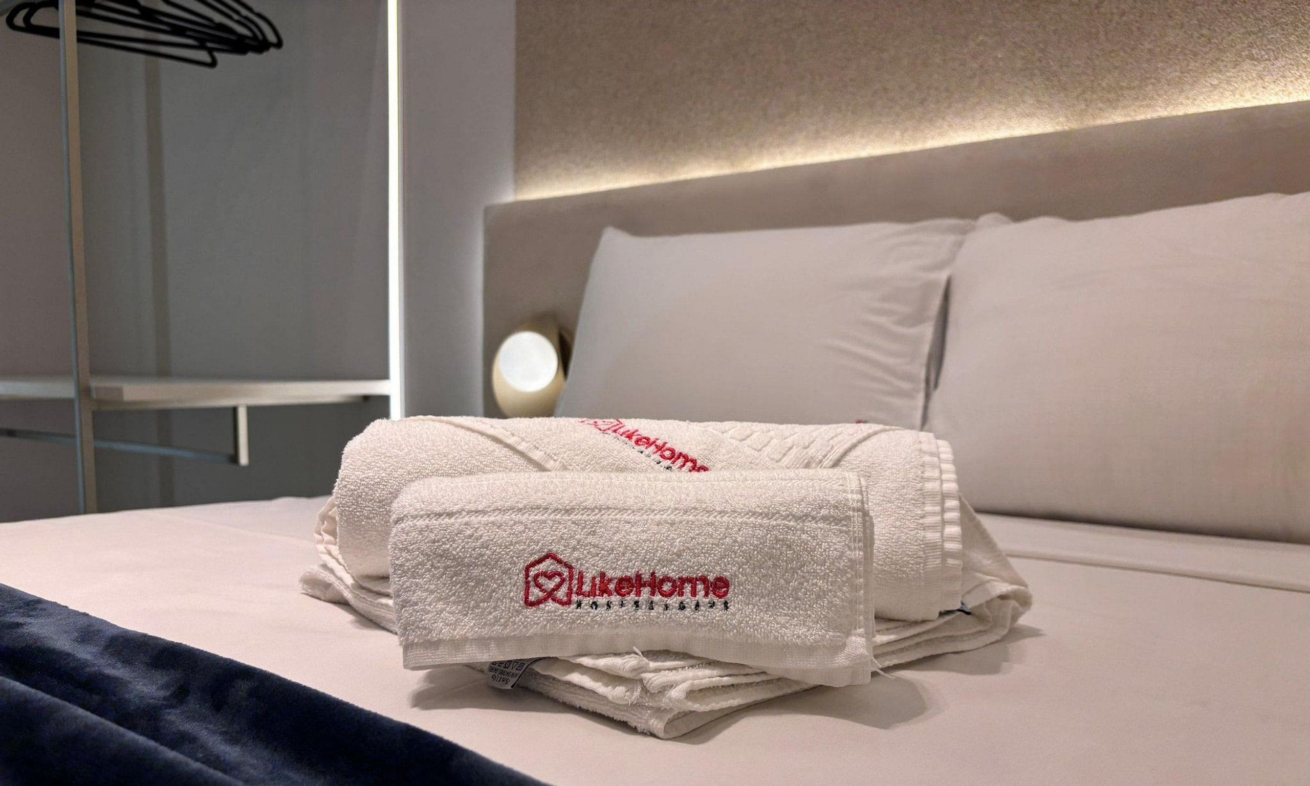 A neatly made bed with a folded towel and a pillow.