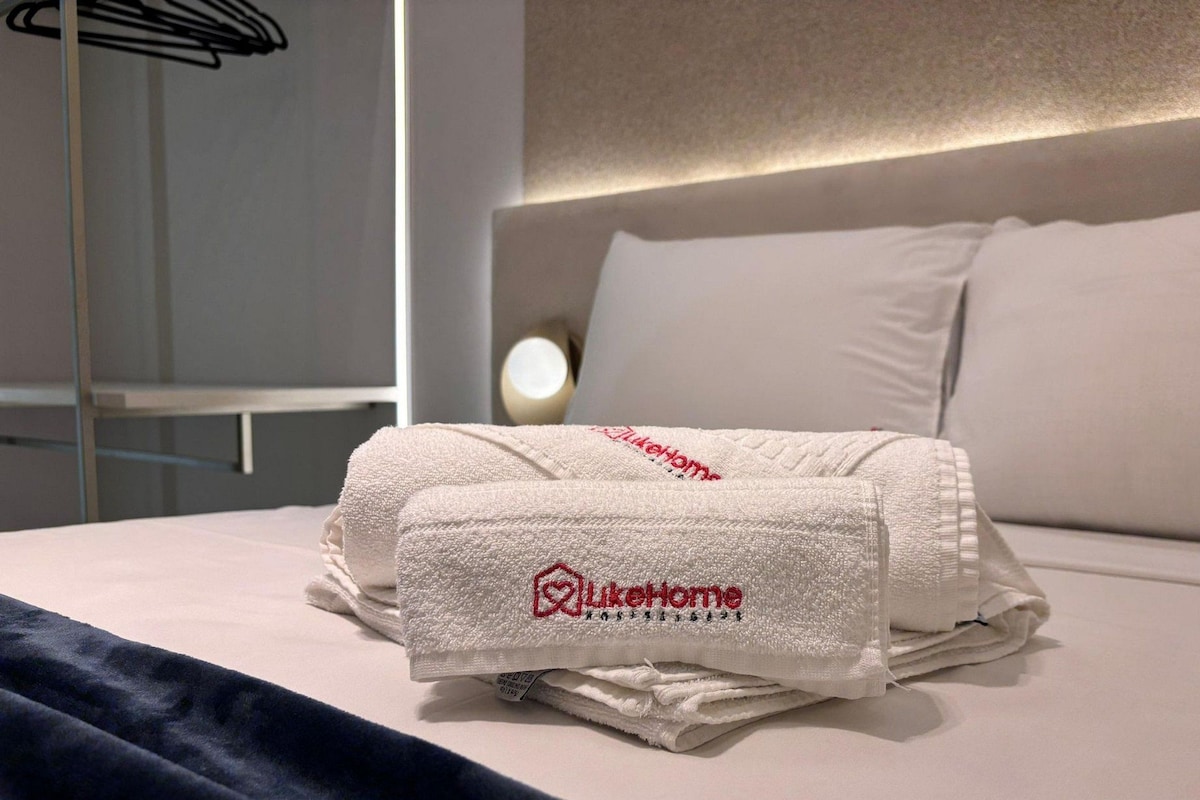 A neatly made bed with a folded towel and a pillow.