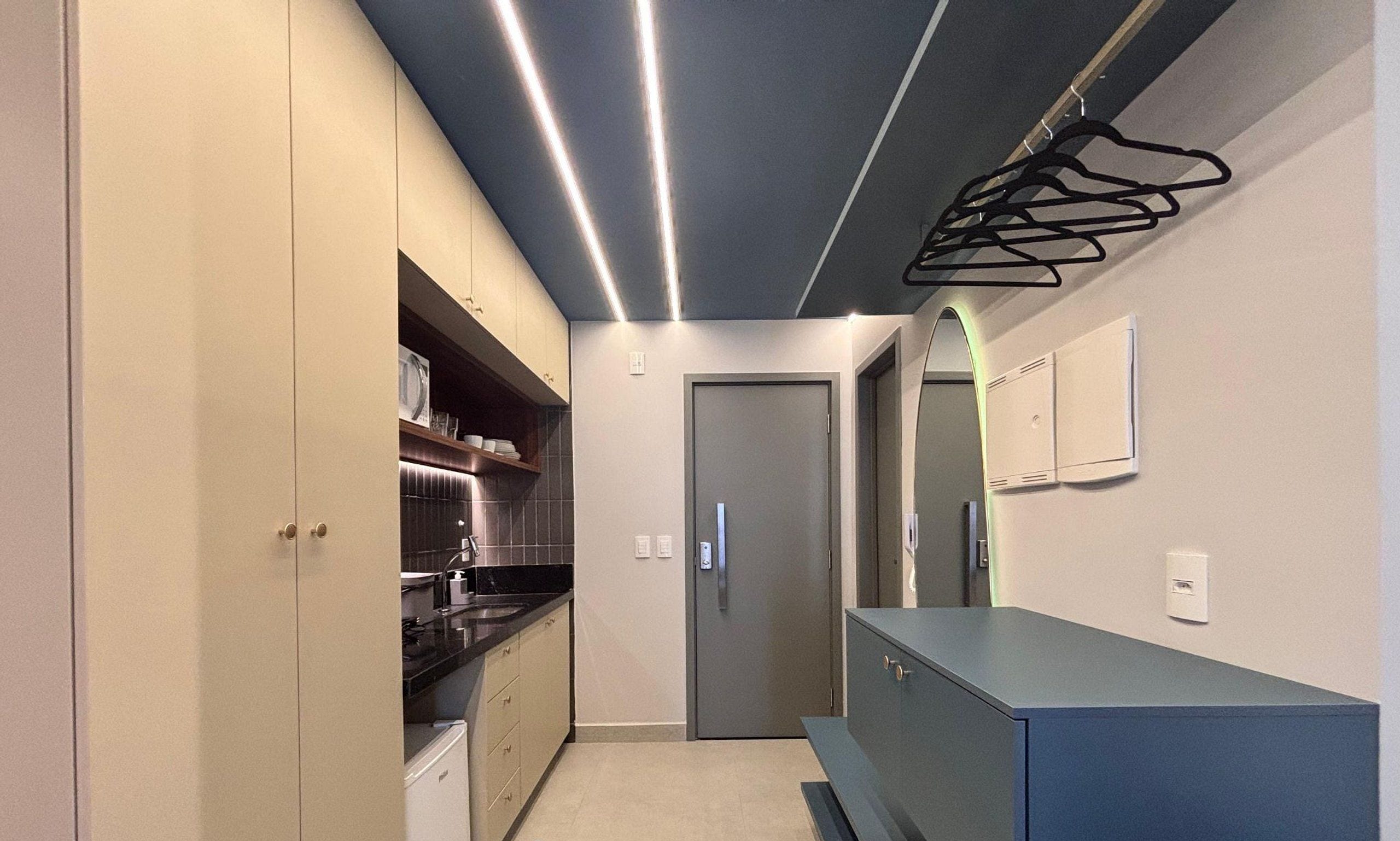 A narrow kitchen with cabinets, a countertop, and a door leading to another room.