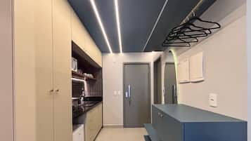 A narrow kitchen with cabinets, a countertop, and a door leading to another room.