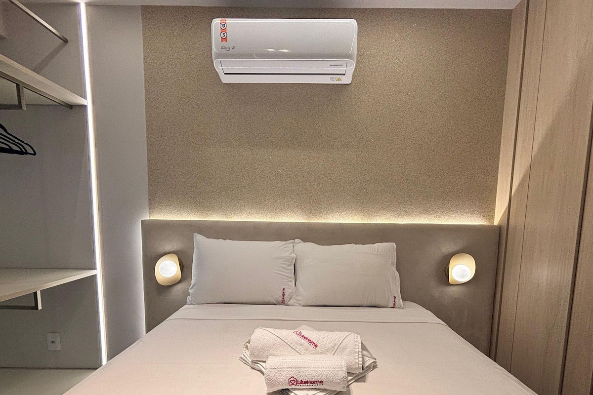 Ein Hotelzimmer mit einem Bett, zwei Nachttischlampen, einer Klimaanlage und einem auf dem Bett gefalteten Handtuch.
