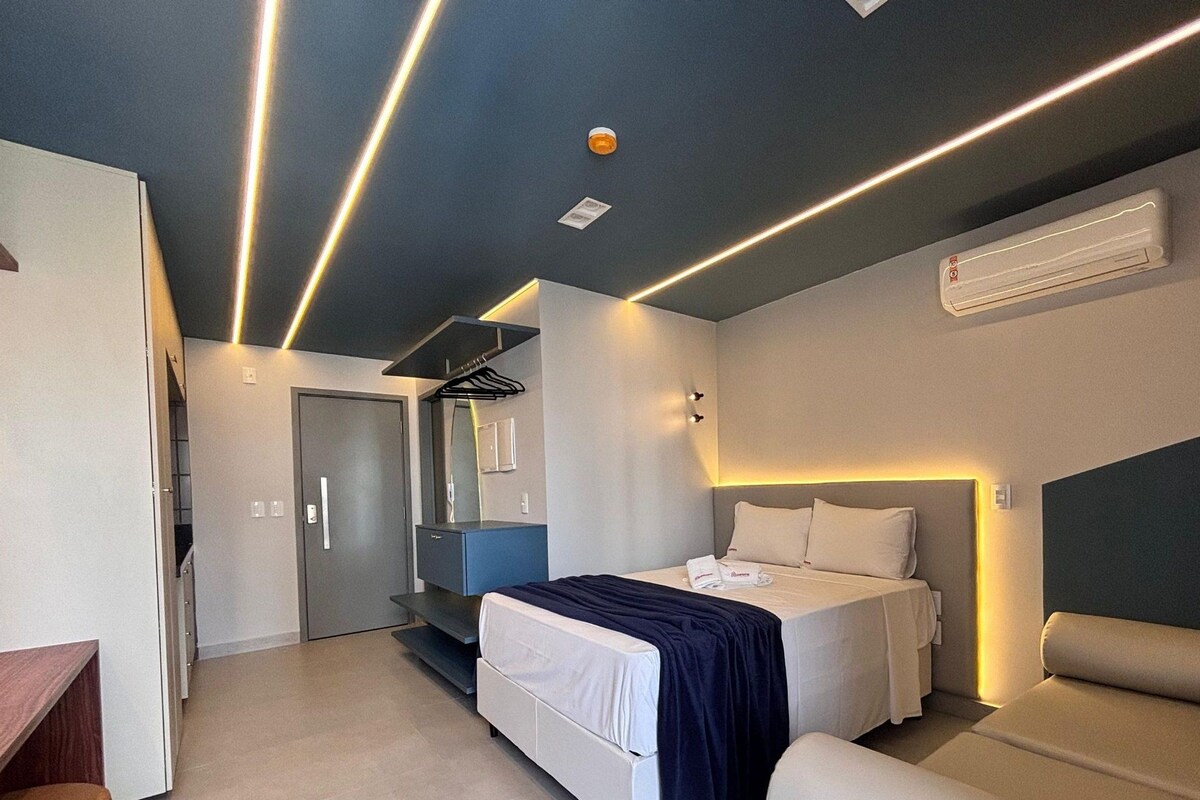 A modern hotel room with a bed, bedside tables, a wardrobe, and a mirror.