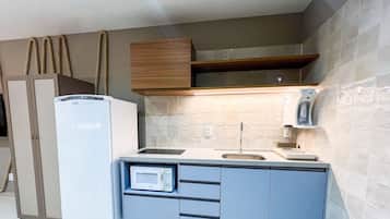 A compact kitchen with a refrigerator, microwave, sink, and wooden cabinets.