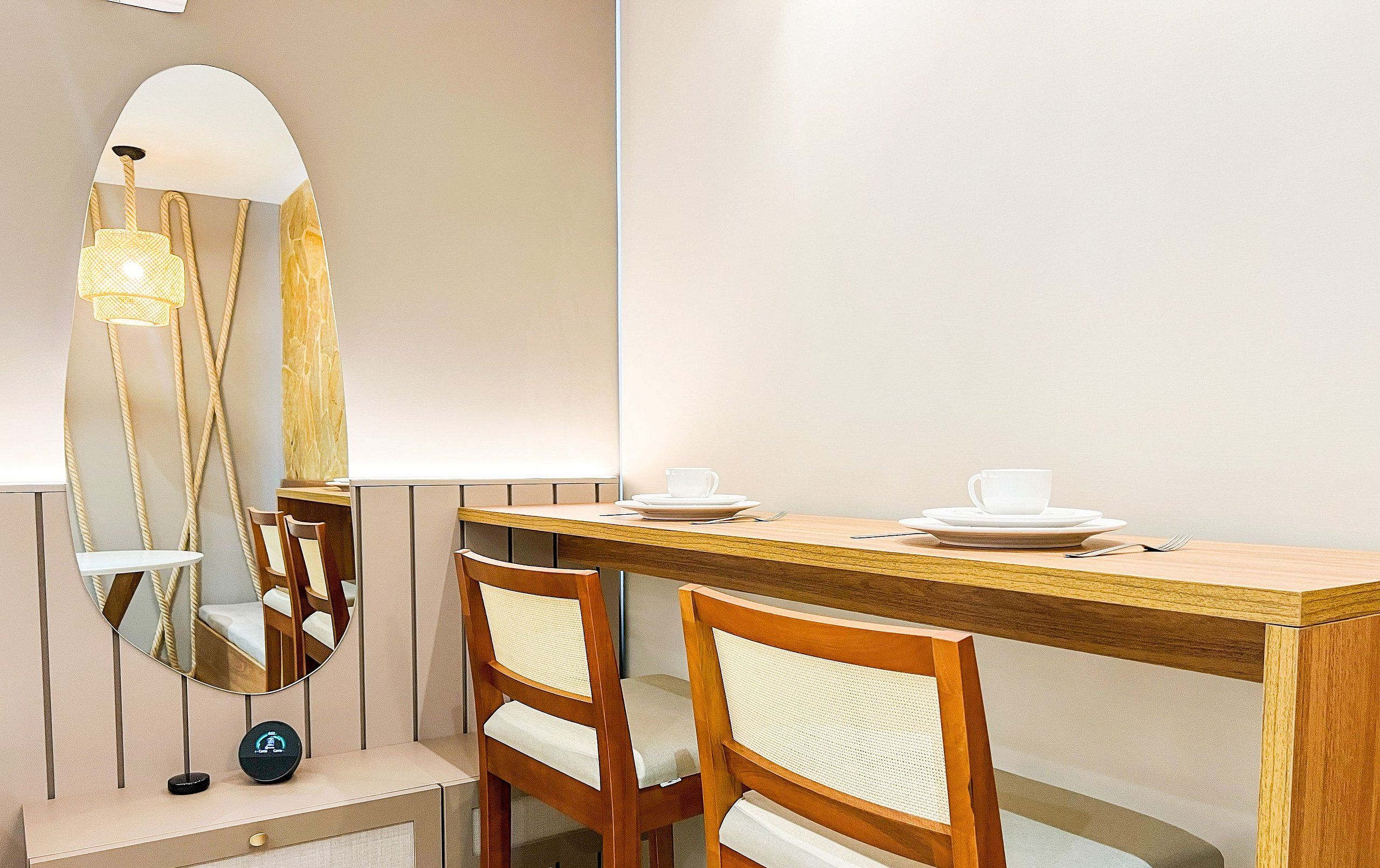 A dining area with a wooden table, two chairs, and a mirror reflecting the room.
