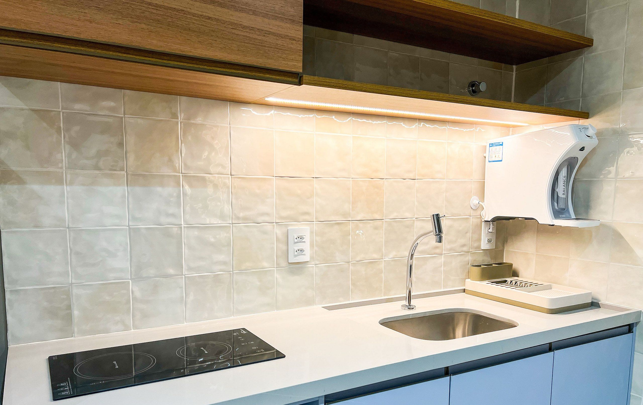 A kitchen with a built-in induction cooktop, a stainless steel sink, and a wall-mounted coffee maker.