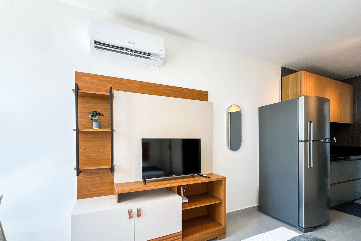 Eine kompakte Küche mit integriertem Kühlschrank, einer Wand-Klimaanlage und einer Holzausstattung mit Fernseher.