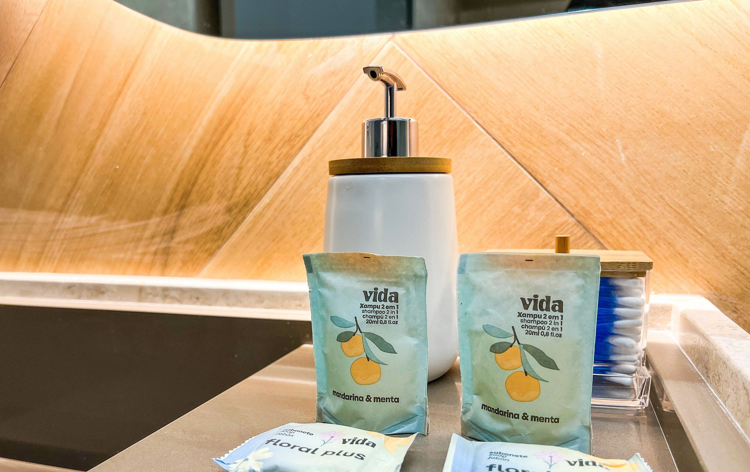 Una encimera de baño con dispensador de jabón, dos botellas de champú y dos de acondicionador.