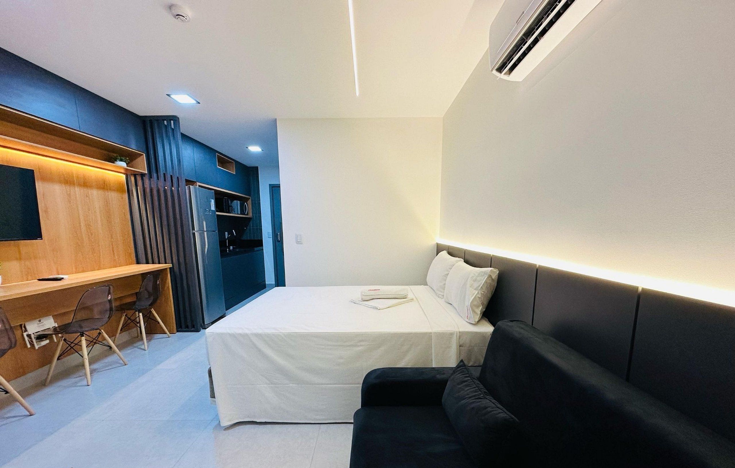 Quarto de hotel pequeno com cama, escrivaninha e sofá.