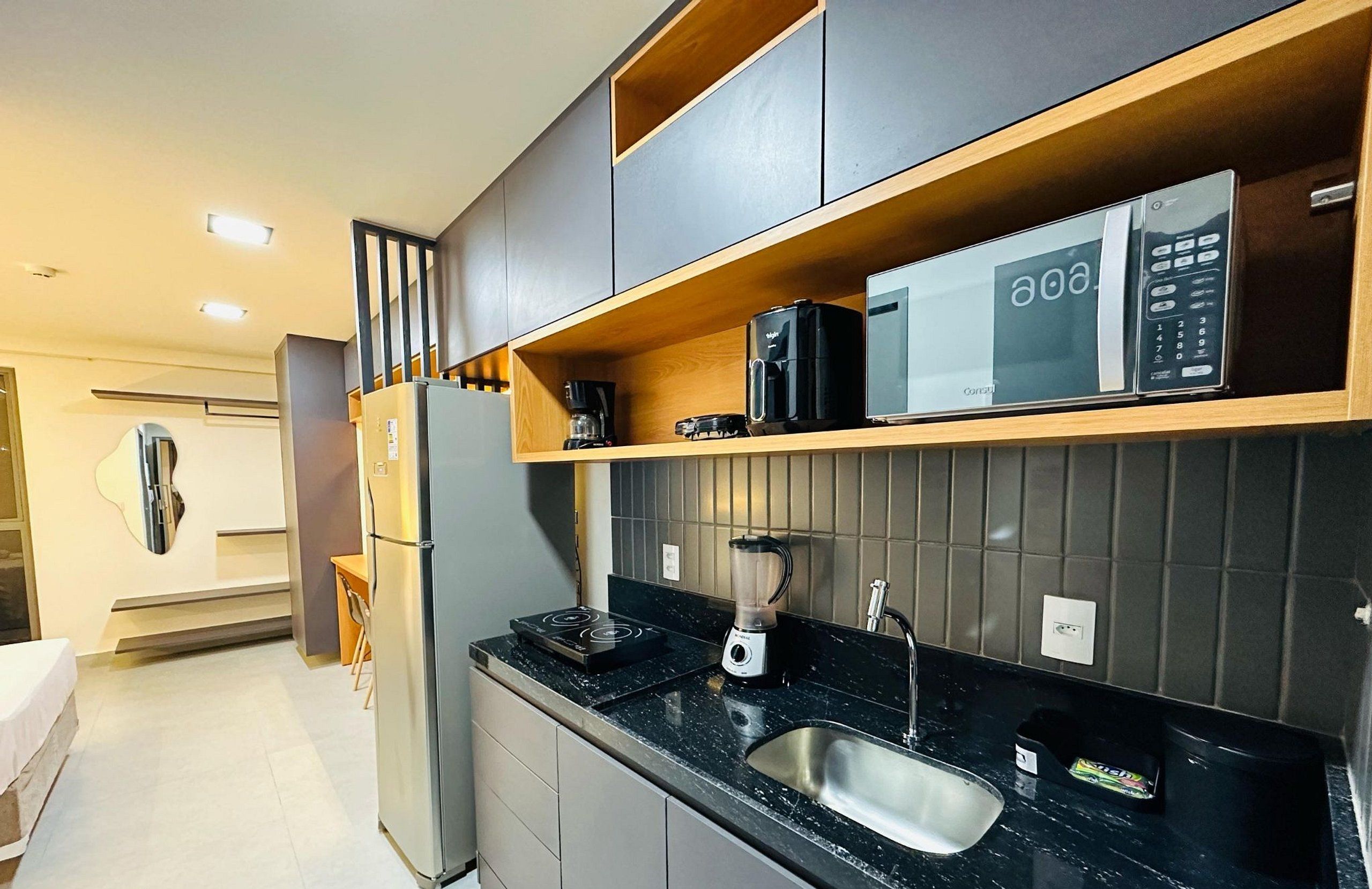 A modern kitchen with a built-in microwave, coffee maker, and blender on the countertop.