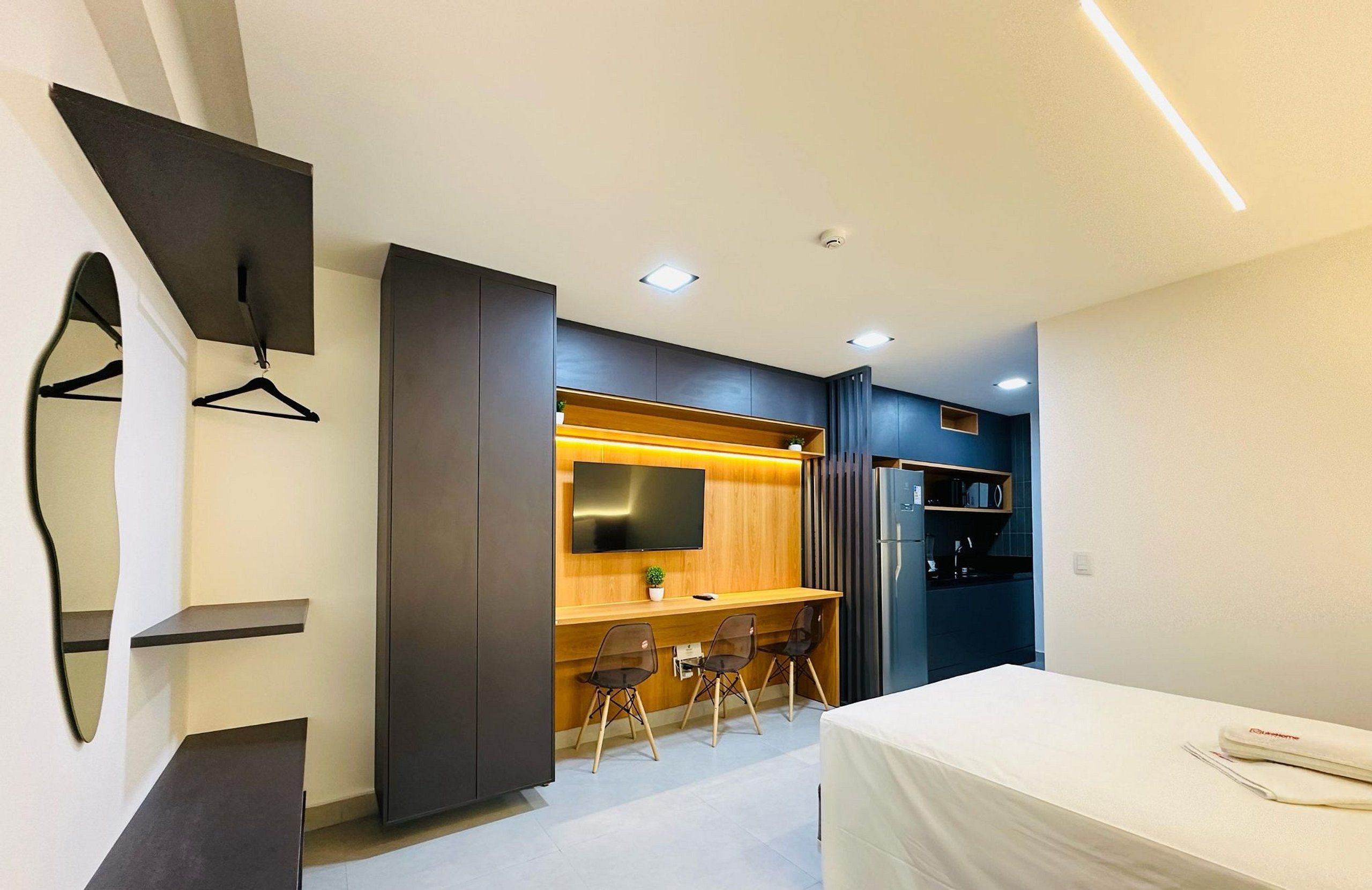Une chambre d’hôtel moderne équipée d’une télévision à écran plat, d’un bureau avec deux chaises, d’un lit et d’une armoire.