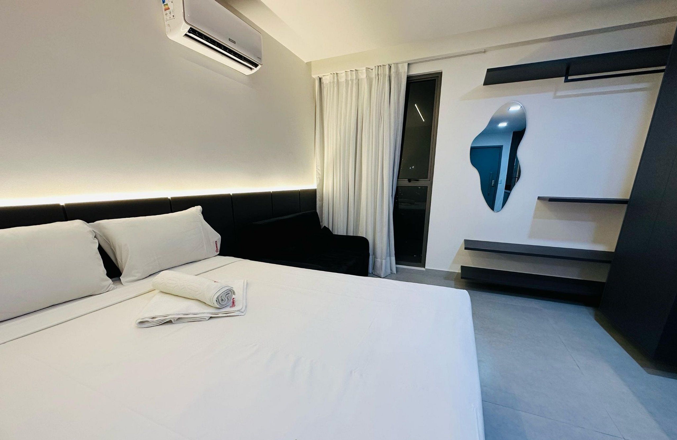 A hotel room with a bed, a desk, a chair, and a window with curtains.