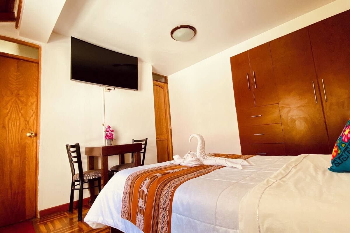 Ein Hotelzimmer mit Bett, Schreibtisch, Fernseher und Kleiderschrank.