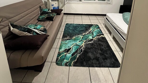 Un espacio habitable compacto con sofá, cama, televisor y ventana con cortinas.