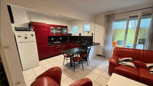 Un espacio habitable compacto con kitchenette, comedor y un sofá de cuero rojo.