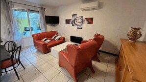 Una sala de estar con sofás de cuero rojo, una mesa de centro, un televisor de pantalla plana y obras de arte en la pared.