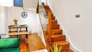 A staircase with wooden steps and a glass railing, leading to an upper floor.