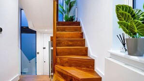 A wooden staircase with a glass railing, leading to a door.