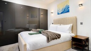 A modern bedroom with a large bed, a wardrobe, and a painting on the wall.