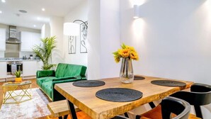 A modern dining area with a wooden table, black chairs, and a green sofa.