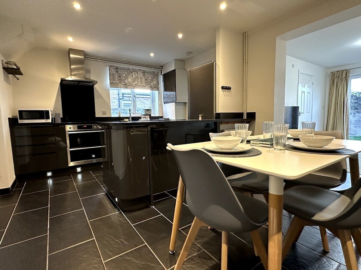 A modern kitchen with a dining area, featuring a central island, built-in oven, and a large refrigerator.