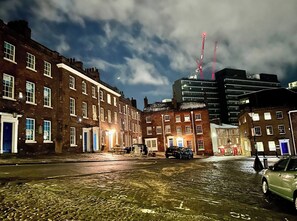 A cobblestone street with historic buildings, a modern skyscraper, and cranes in the background. - Modern Central Edwardian Apartment 4pp Private Ent (Sheffield)