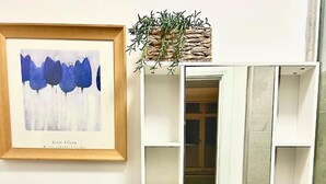 A framed abstract painting, a plant, and a partially open door with a tiled wall.