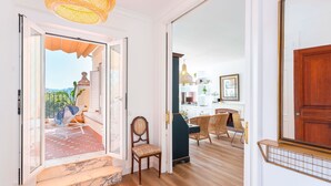 A room with a wooden floor, a chair, a door, and a view of the outdoors. - Penthouse With Private Terrace Stunning Views Plaza de la Marina (Málaga)