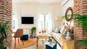 Un soggiorno moderno con televisione, divano, tavolino da caffè e parete decorata con mattoni.