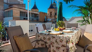 Una terrazza sul tetto con un tavolo apparecchiato per mangiare, affacciata su un edificio storico con torri a cupola.