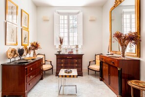 A room with a marble floor, a wooden dresser with drawers, a small table with a decorative item, a mirror, and framed artwork on the wall. - Pretty two bd Apartment Near the Cathedral Pasaje Santa Cruz II (Seville)