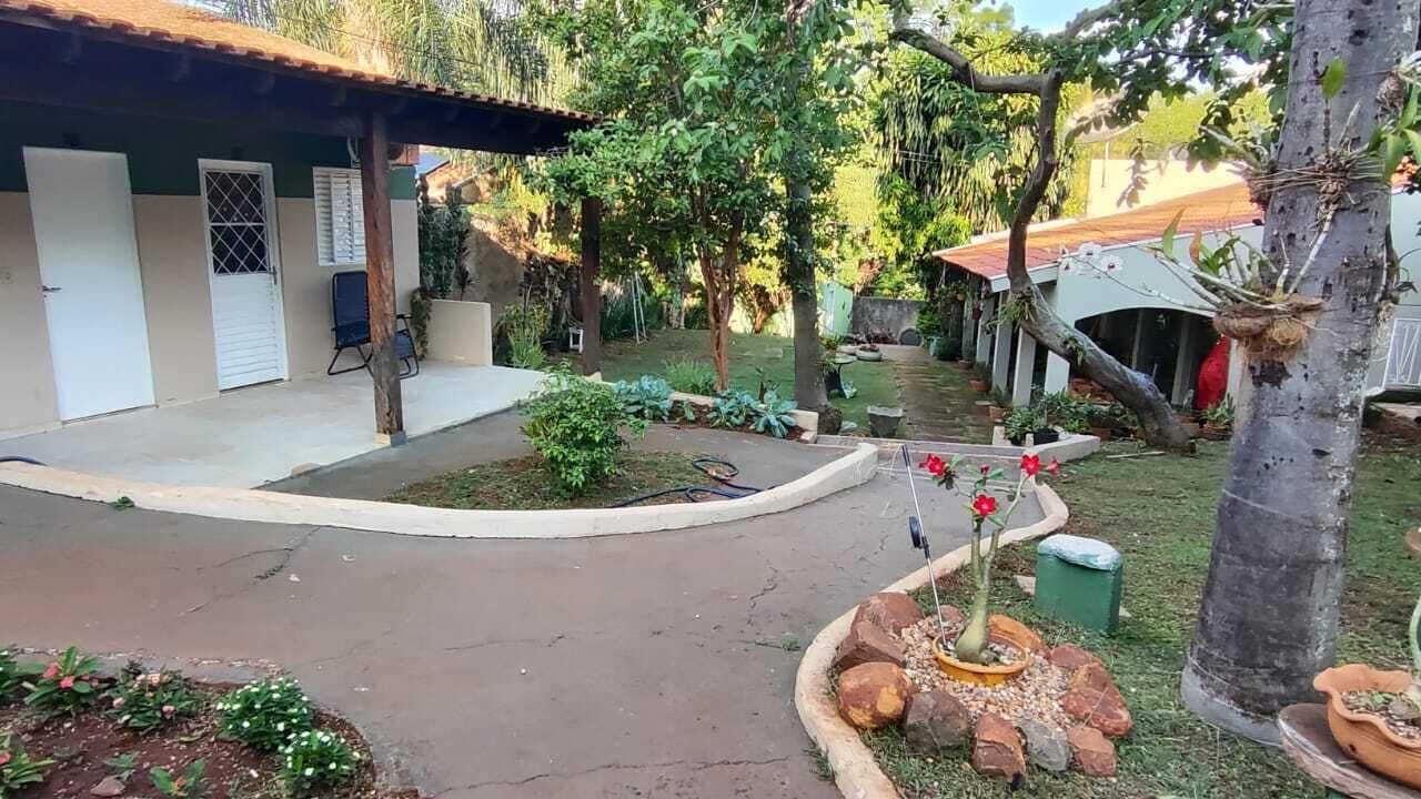 Ein Innenhof mit überdachter Sitzgelegenheit, ein kleiner Garten mit Topfpflanzen und ein Weg zu einem Gebäude mit einem Ziegeldach.