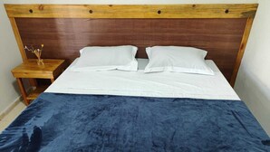 A bed with a wooden headboard, white bedding, and a blue blanket.