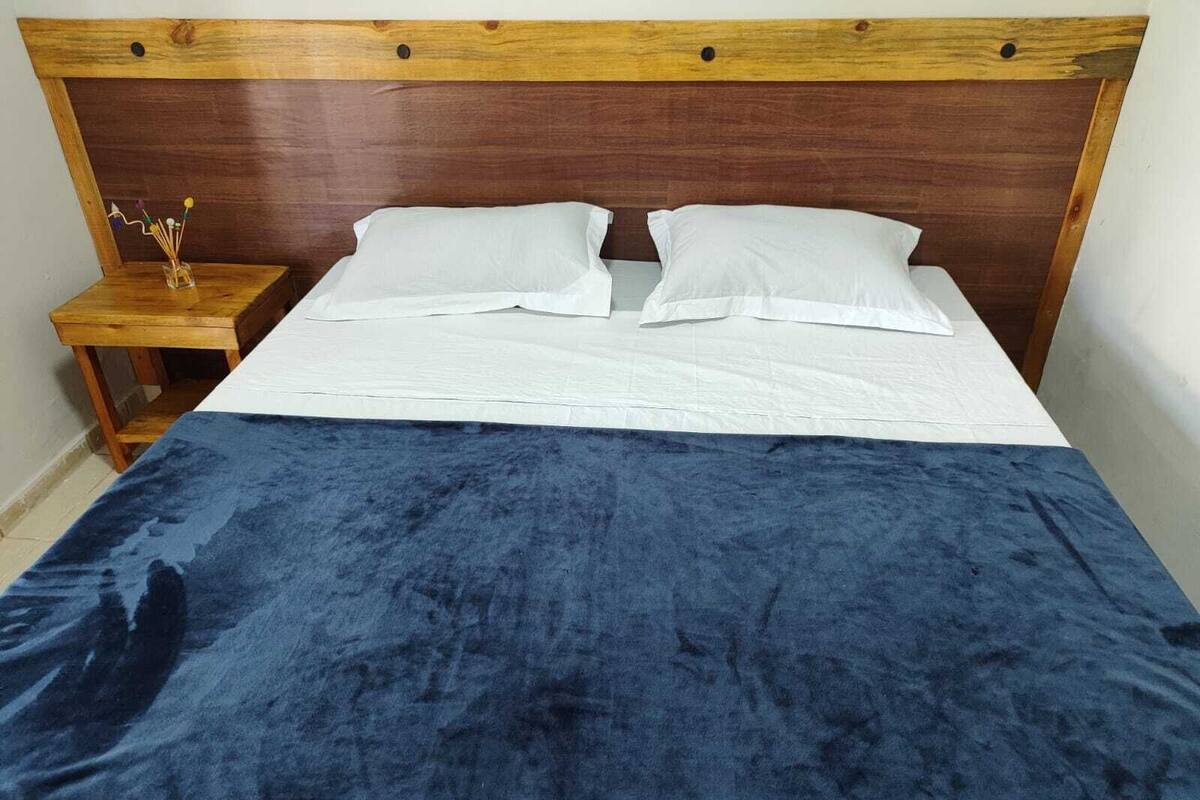 A bed with a wooden headboard, white bedding, and a blue blanket.