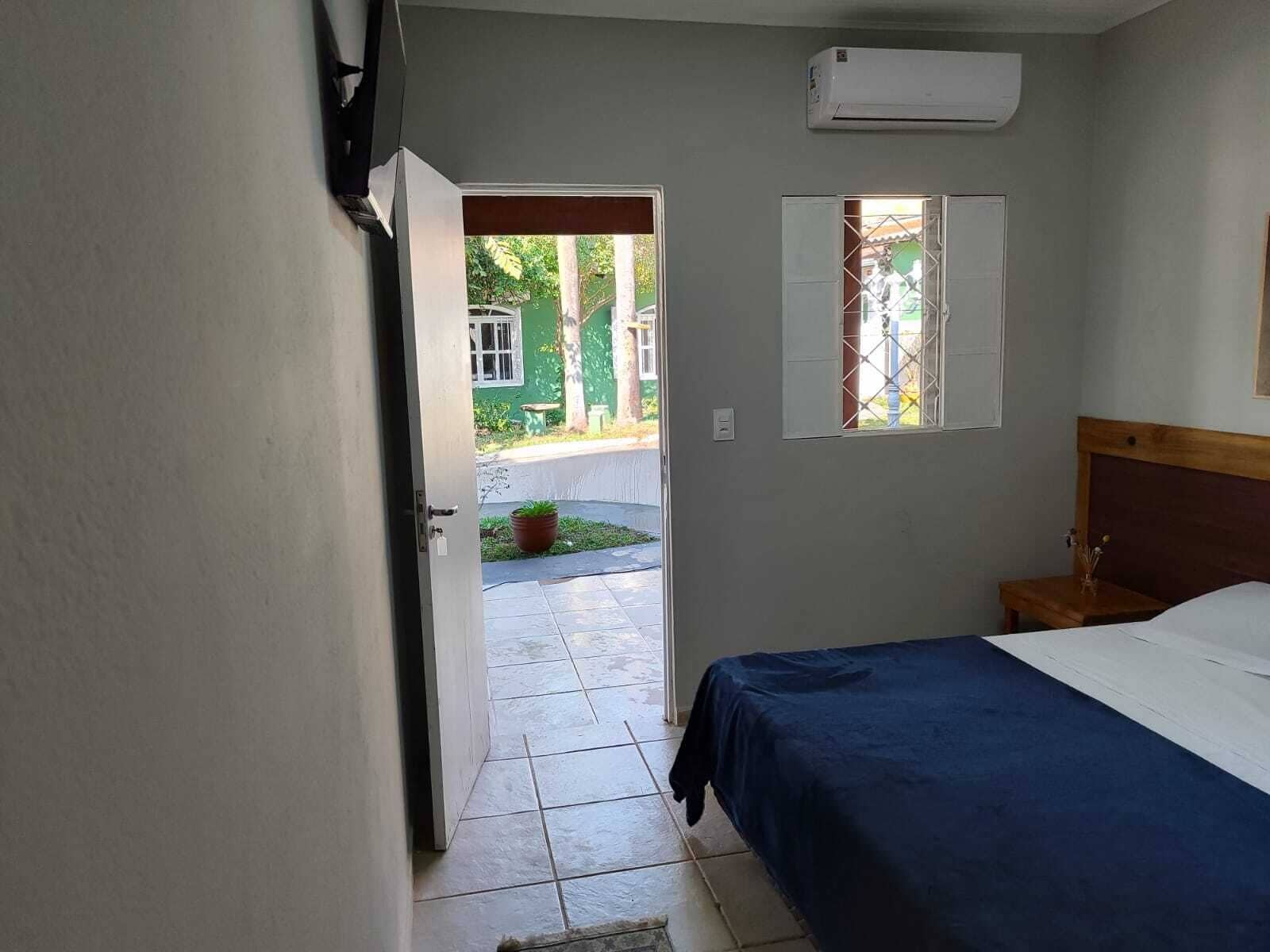 A bedroom with a bed, a window, and an air conditioning unit.