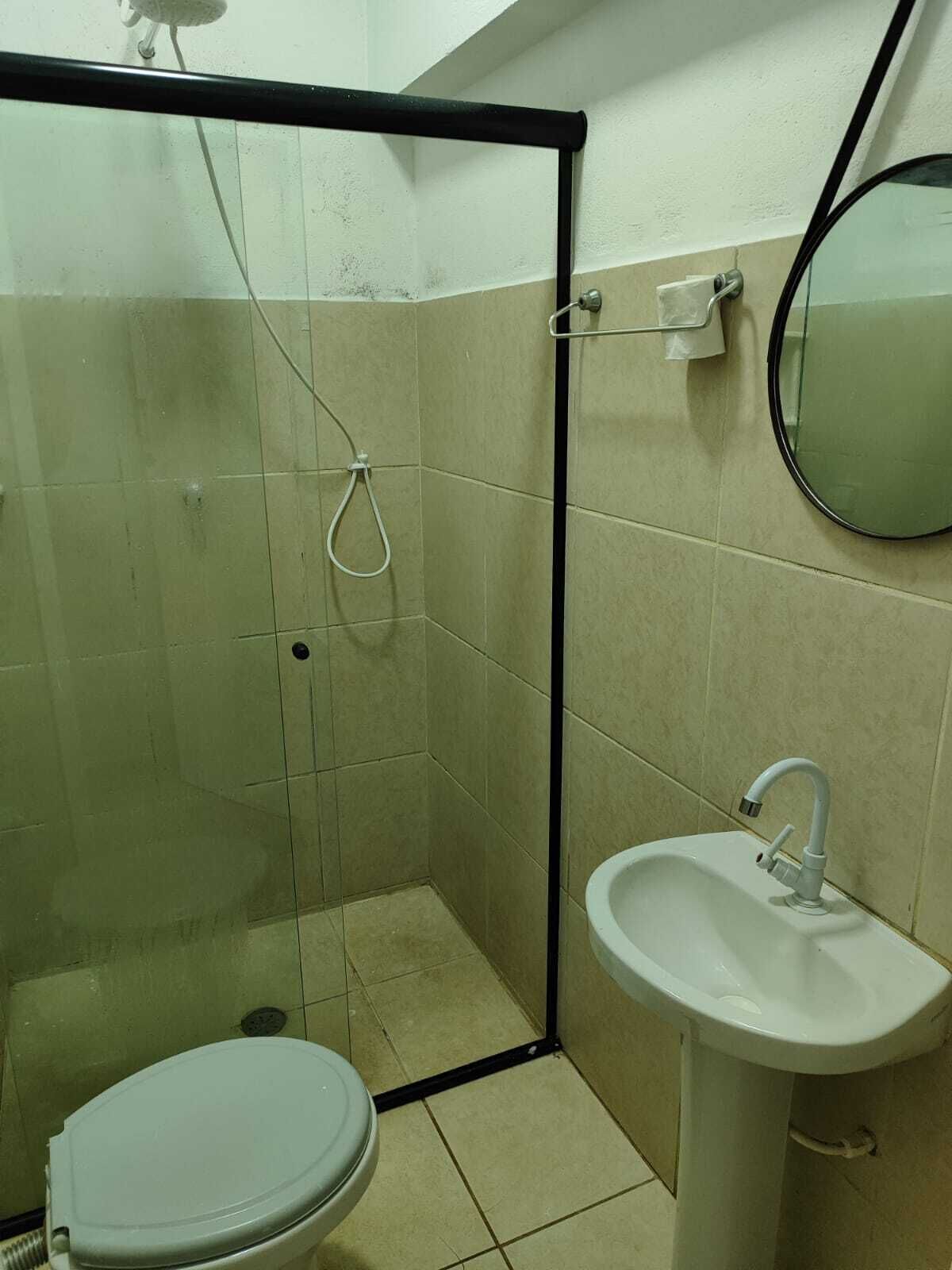 A small bathroom with a toilet, sink, and shower.