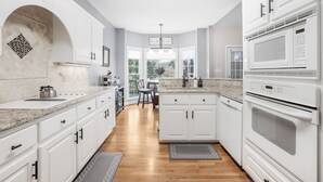 Een moderne keuken met witte kasten, een granieten aanrechtblad en een ingebouwde magnetron.