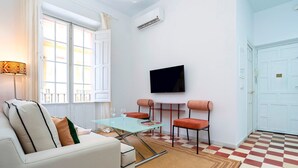 A modern living room with a glass coffee table, a sofa, two armchairs, a flat-screen TV, and a checkered floor. - Private Terrace 5 min Walk to Cathedral 2Bd Apartment Galera II (Seville)