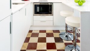 A compact kitchen with white cabinets, a red toaster, a black oven, and a checkered floor. - Private Terrace 5 min Walk to Cathedral 2Bd Apartment Galera II (Seville)