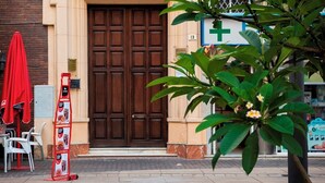 Un edificio con una puerta de madera grande, un paraguas rojo y un letrero que muestra imágenes de comida.