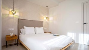 Une chambre moderne avec un grand lit, des tables de chevet et des lampes suspendues.