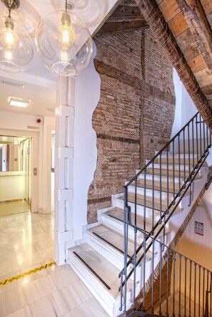 A staircase with a brick wall, a white door, and a metal railing. - Stunning 2-bedroom Apartment Near Cathedral Zacatin 303 (Granada)