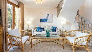 A living room with a sofa, two wicker chairs, a glass coffee table, and a painting on the wall. - Stunning 4 Bedroom House in Albaicin Alhacaba (Granada)