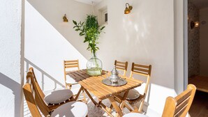 A wooden table with chairs, a hanging plant, and wall-mounted lights in a bright room with white walls. - Stunning 4 Bedroom House in Albaicin Alhacaba (Granada)