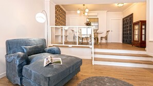 Un salon avec un canapé gris, un tapis rond et un coin repas comprenant des chaises et une table.