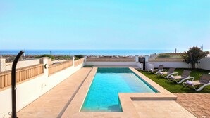 A rooftop pool with a clear view of the ocean, surrounded by lounge chairs and a low wall. - Spectacular House With Private Pool on the Beachfront Mirador de La Barrosa (Chiclana de la Frontera)