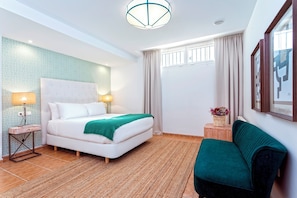 A hotel room with a bed, bedside lamps, a green sofa, a window with curtains, and a wall-mounted picture. - Spectacular House With Private Pool on the Beachfront Mirador de La Barrosa (Chiclana de la Frontera)