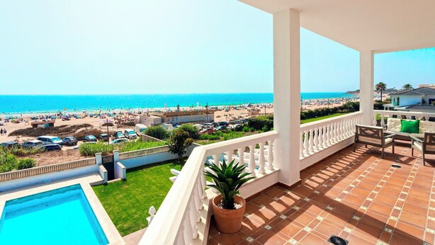 A balcony with a view of the beach, a swimming pool, and a potted plant. - Spectacular House With Private Pool on the Beachfront Mirador de La Barrosa (Chiclana de la Frontera)
