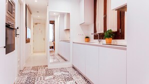 Una cocina moderna con armarios blancos, piso de baldosas estampadas y una planta en maceta sobre la encimera.