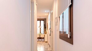 Un pasillo estrecho con piso estampado que lleva a un comedor con una mesa y sillas.