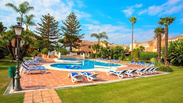 A pool area with lounge chairs and palm trees. - Spectacular Apartment With Pool and Direct Acces to the Beach Venalmar Terrace (Estepona)
